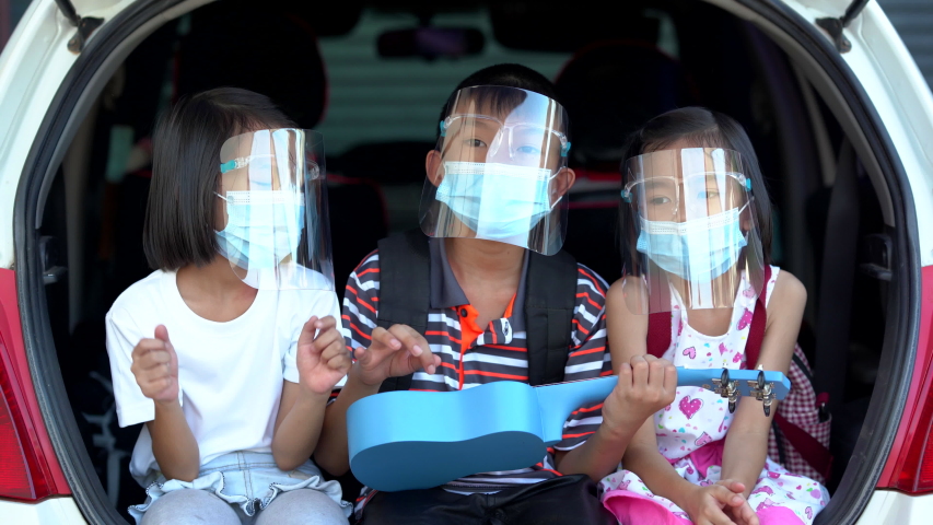 Happy kid on trunk car and sing a song, brother and sister wearing mask and face shield for protect and safety coronavirus | Shutterstock HD Video #1054246088