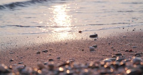 Close up calm waves ripple on sand, defocused pebbles foreground, Almeria, Spain