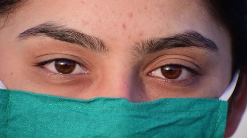 Female face in medical face mask for virus infection prevention and protection, Pandemic protection of the Covid-19 coronavirus. Woman with green eyes in protective medical mask. shot in 4k resolution