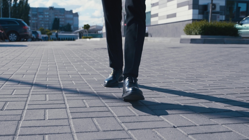 Front view feet of businessman commuting to work. Confident guy in leather shoes and a suit walks along the street of the business district | Shutterstock HD Video #1054249976