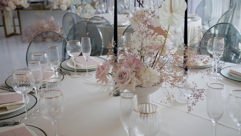 Decorated dinner table with a vase of roses, gypsophila and calla lilies in white and pink. Floral composition from a fresh bouquet for a wedding event.