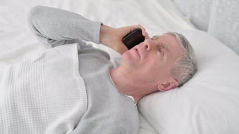 Old Man Talking on Smartphone in Bed 