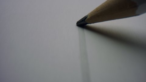 Graphite pencil drawing straight line on white paper background. Macro of pencil writing flat line in slow motion. Closeup unknown person drawing line on paper.