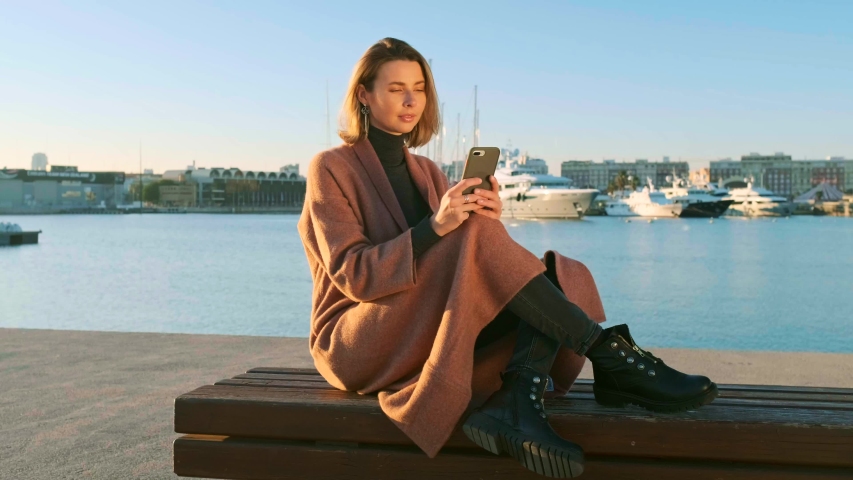 Young beautiful modern woman in headphones listens to music on a smartphone