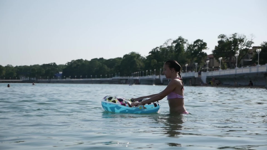 Baby girl swims in the sea on an inflatable circle and falls into the water