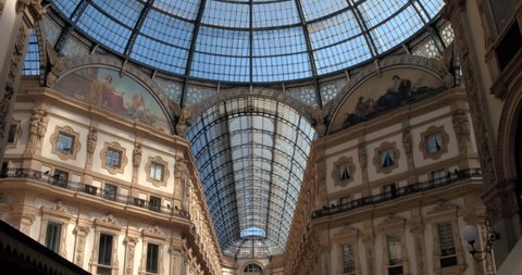 Milan, Italy - June 5, 2020: Descovering iron and glass dome in the middle of Vittorio Emanuele II gallery, near Piazza Duomo, in a spring sunny day. Arches and frescoes