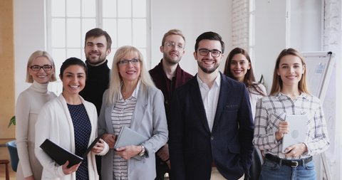 Group portrait of happy middle aged and young multiracial confident employees posing for corporate photo in office. Smiling team of diverse different generations business people looking at camera.