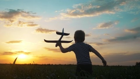 happy boy child run with an airplane. kid silhouette play plane. happy family dream freedom airplane concept. lifestyle son kid run on wheat field at sunset holds in his hands dream toy aircraft