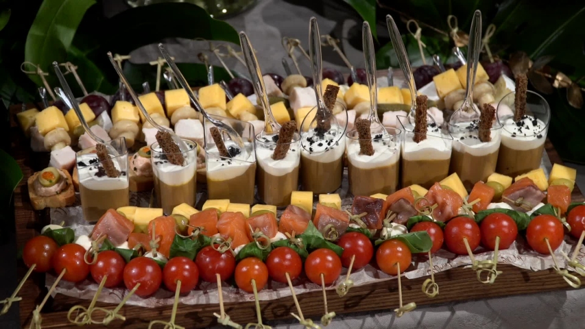 A snack set of salmon fish, caviar, cheese, tomatoes, olives, pate and mushrooms on skewers at banquet event in hotel restaurant. Beautifully decorated gourmet appetizers for guests at stand-up meal.