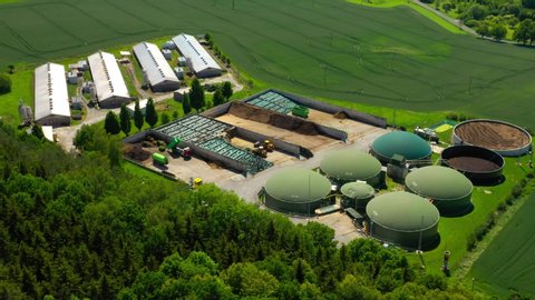 Biogas plant and farm in green fields. Renewable energy from biomass. Aerial view to modern agriculture in Czech Republic and European Union. 