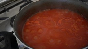 Sauce boiling in a pan seen from above. homogeneous sauce prepared with different ingredients and used as a sauce for pasta or rice. In Italy it is traditionally based on tomato