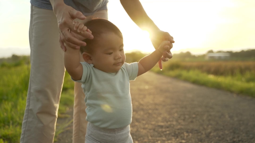 mother help her baby to walk her first step on country road Royalty-Free Stock Footage #1054283732