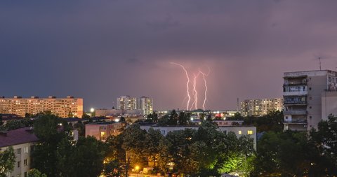 Looping time lapse of lightning strikes above city buildings during a heavy storm, at dusk, in Bucharest, Romania, Eastern Europe.