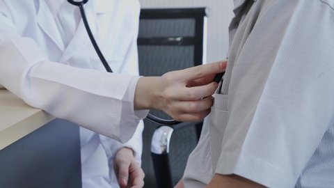 Close-up of a hand of a female doctor using a stethoscope to checking lung for a middle-aged patient who has a fever and comes to see the doctor at the health care center.