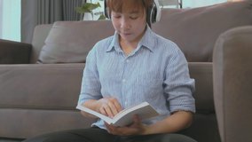 Young Asian woman is reading book and listen Music  at home in the morning