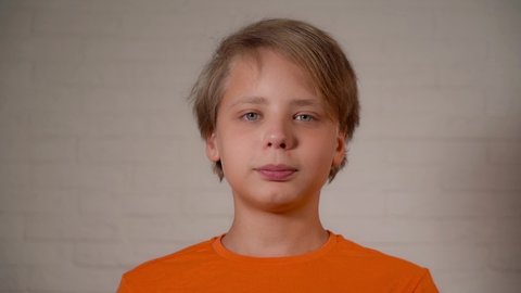 Closeup view video portrait of cute white kid looking at camera smiling calmly. Age of boy 13 years old.
