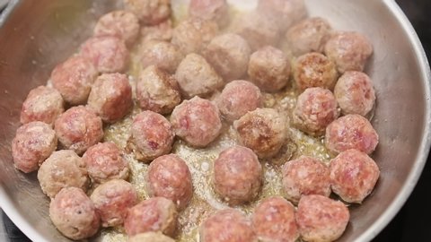 Stirring and frying of delicious small meatballs in frying pan.