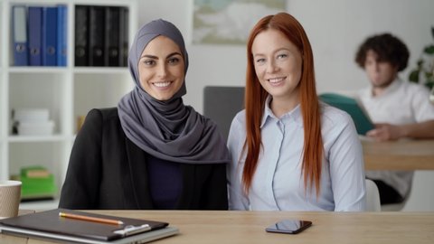 Arab and European women looking at the camera and smiling