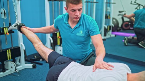 Rehabilitation concept. Young man doing exercises under physiotherapist supervision