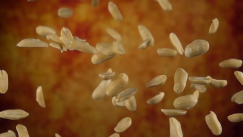 Peeled tasty peanuts are bouncing on a yellow ochre background in slow motion