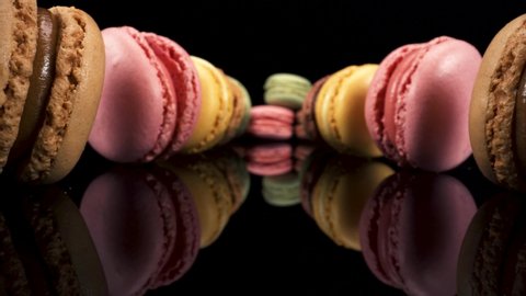 Macro viewing past macarons on black reflective glass, sweet tasty desserts interesting low down perspective