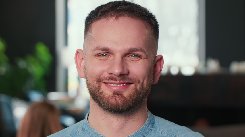 Close-up portrait of happy young smiling cheerful Caucasian freelancer businessman looking at camera at modern office.