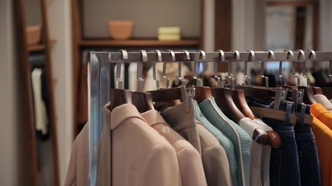 On the hangers are a lot of clothes of various colors. An assortment of women's clothing in a store. Panorama of dresses, jackets, shirts, skirts and other clothes