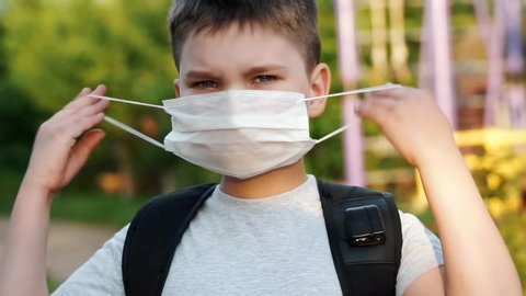 child boy putting on surgical mask for coronavirus prevention. Back to school. Portrait of preteen kid in protection mask. health medical care and safety, flu virus, pandemic, air pollution protection