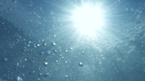 From sky with clouds  through under water's Sun Light Rays glittering. Natural slow motion underwater scene 