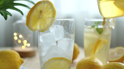 Healthy iced lemon drink for detoxification poured in glasses. Iced lemon drink is a healthy beverage for detoxification. Some might drink lemon infused water with gin for cocktail.  Pouring concept.