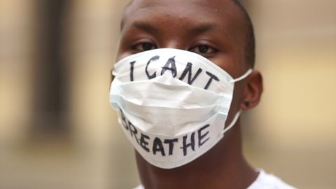 Black lives matter, mass protests against racism in the USA and Europe. Outdoor portrait of a African American in a medical mask with the inscription I cant breathe