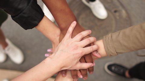 Youth interracial companies lay their hands on top of each other as a sign of support and solidarity. Mass protests in the US and Europe against violence and racism