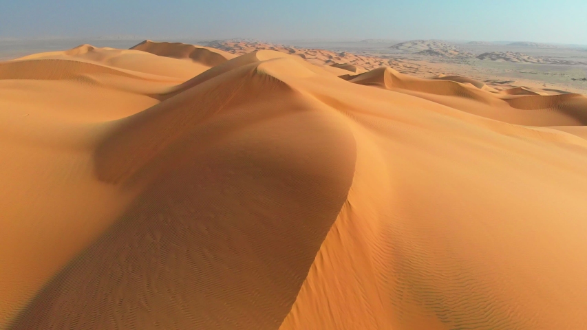 Rub' al Khali, aka Empty Quarter desert, Arabian Peninsula. Flying over curve shaped sand dunes during hot summer weather. Aerial shot, 4K Royalty-Free Stock Footage #1054311698