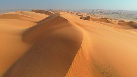 Rub' al Khali, aka Empty Quarter desert, Arabian Peninsula. Flying over curve shaped sand dunes during hot summer weather. Aerial shot, 4K