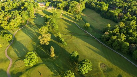 Aerial view of Golf course. Establishing shot, drone flying over golf club. Early morning, summertime, sunlight