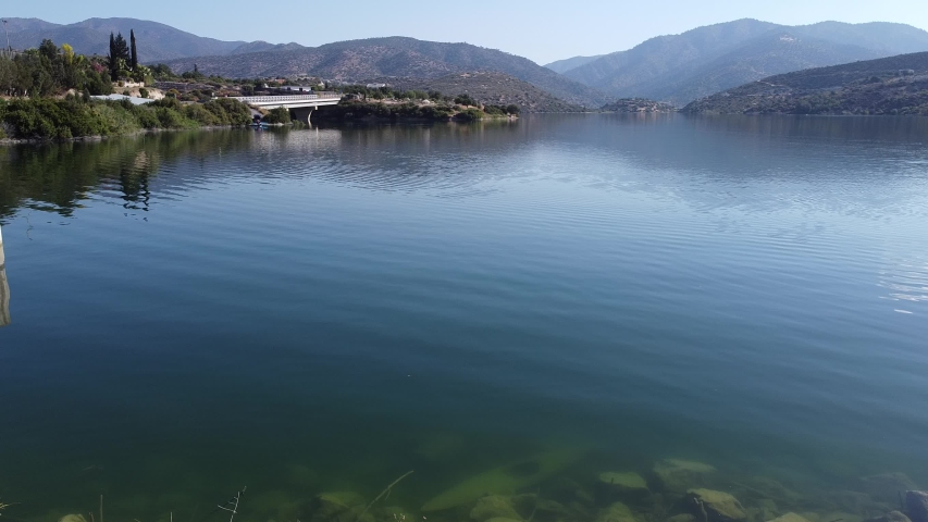 A sunken kayak at the bottom of a reservoir against a mountain landscape