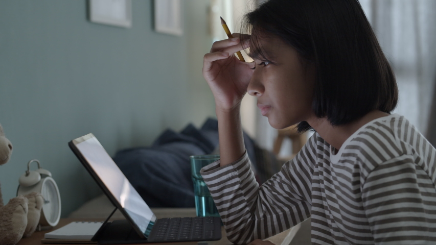 Boring asian girl is studying online via the internet on tablet at home night. Concept distance learning at home | Shutterstock HD Video #1054315394