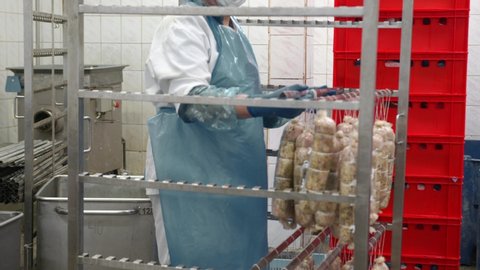 Worker of the sausage Department, puts the sausage on the shelf of the drying Cabinet. Preparation for baking sausage.