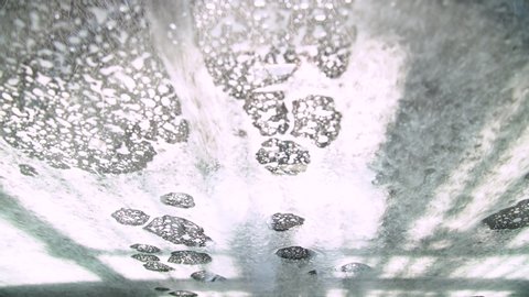 Close up view from inside the car in conveyor tunnel car wash. Washing car with soap and water, rotating brush in automatic car wash service
