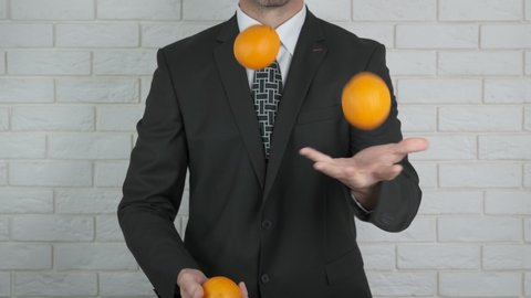Business with mandarines. A person in a suit juggle with mandarines. A concept of business with mandarines.