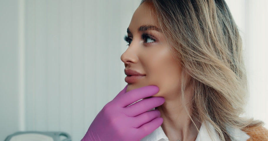 Cosmetologists touching and examining facial skin of a female. Woman face being checked by beauticians | Shutterstock HD Video #1054323155