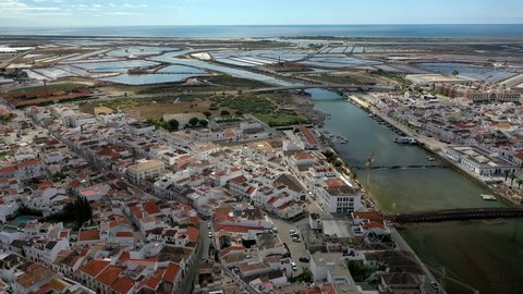 Aerial View over Gilao River. Sunny day at Tavira City, in Algarve, Portugal. Old Roman Bridge and other under construction. Drone Rotating camera move