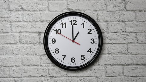 The Time Is 1.00 AM Or PM On A Black Wall Clock With A Red Second Hand On A White Brick Wall