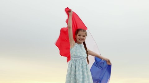 A teenage girl holds the French national flag in the Summer sunset. The Bastille day on July 14. The day of France. 4K