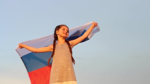A teenage girl holds the Russian national flag in the Summer sunset. Russia day on June 12. The day of the Russian flag on August 22. 4K