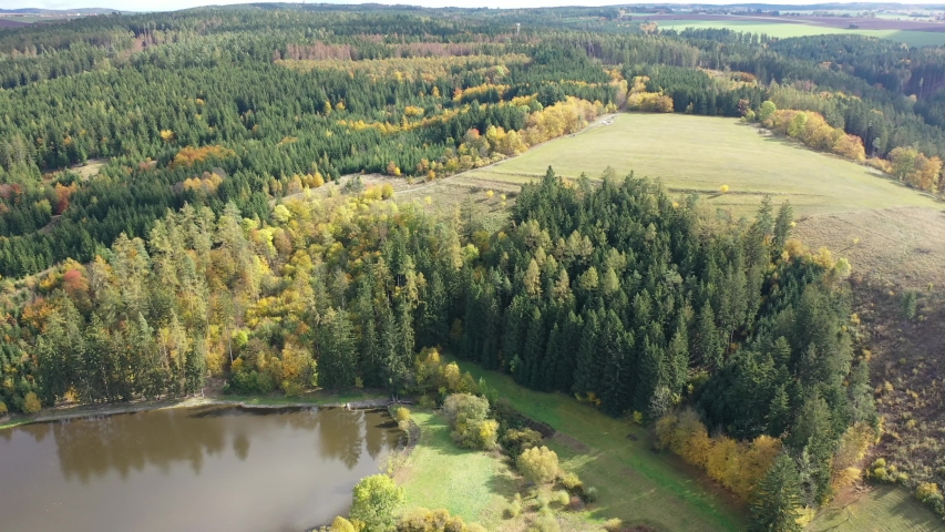 View from drone of forest landscape around picturesque lake on sunny autumn day