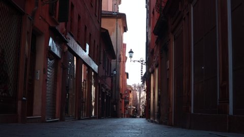 Old and narrow street in Bologna downtown with cyclist passing by