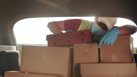 delivery pandemic covid coronavirus vaccine a goods and food product. man volunteer works stacks boxes in a car. parcel delivery concept. courier driver in gloves loads boxes during coronavirus