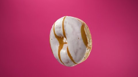 Isolated donut rotates on pink background. A beautiful footage of sweets for children and adults. Gourmet breakfast. Not healthy food, junk food.