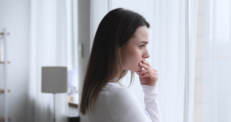 Head shot side view upset worried young brunette woman, looking out of window, thinking of problems. Depressed nervous millennial lady feeling doubtful about hard decision, mental stress concept. Royalty-Free Stock Footage #1054332320